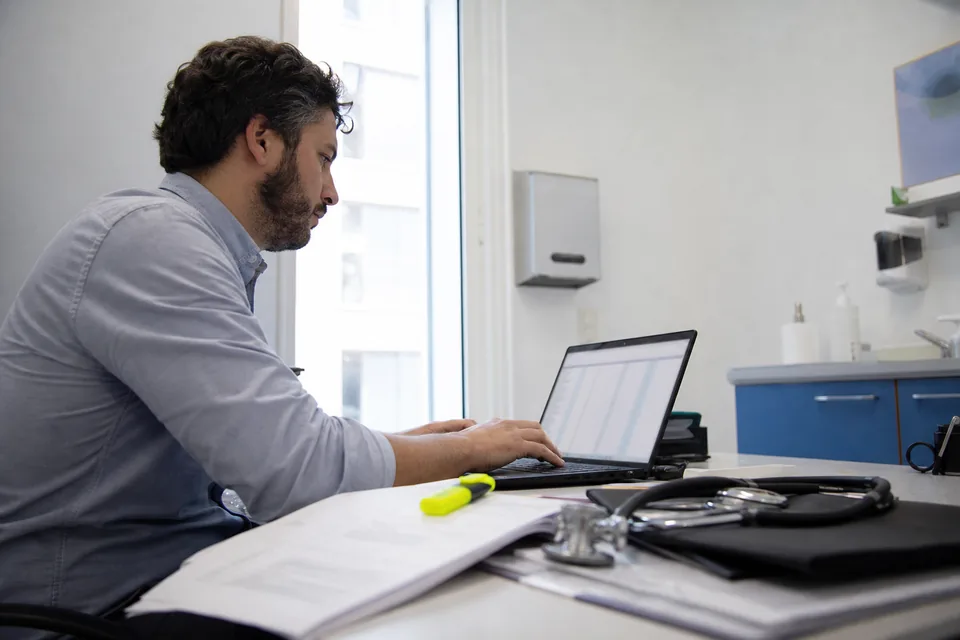 Researcher typing beside printed study pages